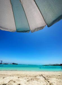 a beach with an umbrella and the ocean at Apartamento BLUE OCEAN Complex Amaya Fuerteventura in Costa de Antigua