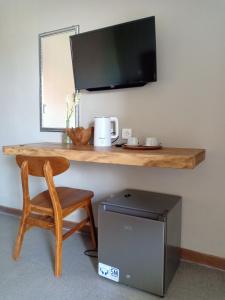 escritorio con silla y TV en la pared en Kasapa Inn en Ubud