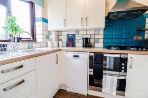 a kitchen with white cabinets and blue tiles at Spacious 1 bed flat-FREE Parking in New Bedfont