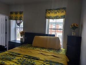 una camera da letto con un letto con un piumone giallo e due finestre di NG-UGI Home a Lebanon