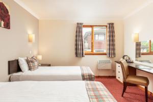 a hotel room with two beds and a desk at Highlander Hotel ‘A Bespoke Hotel’ in Newtonmore