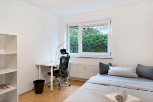 1 dormitorio con cama, escritorio y ventana en City Apartment Ravensburg, en Ravensburg