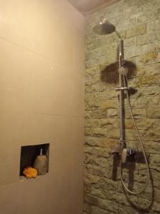 y baño con ducha y pared de piedra. en Kasapa Inn en Ubud