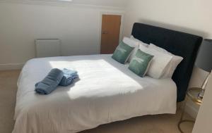 a large white bed with two blue pillows on it at Addlestone - Large Stunning 2 bed room Apartment in Addlestone