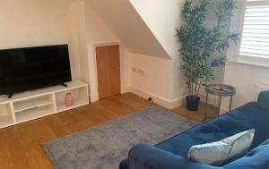 a living room with a blue couch and a flat screen tv at Addlestone - Large Stunning 2 bed room Apartment in Addlestone