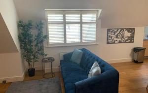 a blue couch in a living room with a window at Addlestone - Large Stunning 2 bed room Apartment in Addlestone