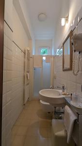 La salle de bains blanche est pourvue d'un lavabo et d'une douche. dans l'établissement B&B Casa Dei Grilli, à Longiano