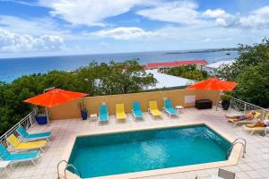 een zwembad met stoelen en parasols en de oceaan bij Villa Sea Forever @ Pelican Key - Paradise Awaits! in Simpson Bay