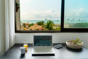 a laptop computer sitting on a desk in front of a window at apartamento vista mar 2 quartos estacionamento gratis Netflix e self check in in Maceió