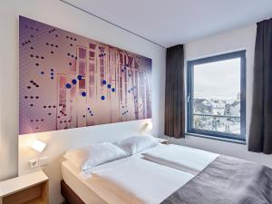 1 dormitorio con 1 cama y una gran pintura en la pared en B&B Hotel Köln-Troisdorf, en Troisdorf