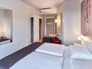 a hotel room with a bed and a desk at B&B Hotel Köln-Troisdorf in Troisdorf