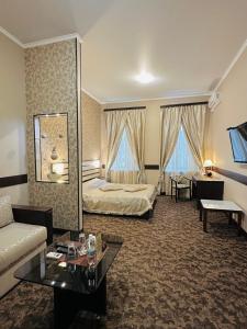ハルキウにあるClassic Hotelのベッドとソファ付きの広いホテルルームです。