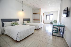 a bedroom with two beds and a table in it at Hotel & Suites Arges - Centro Chetumal in Chetumal