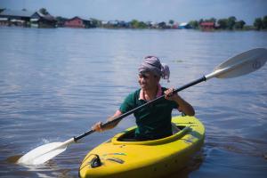 a woman in a yellow kayak on the water at Mechrey Tonle Camp Site in Siem Reap
