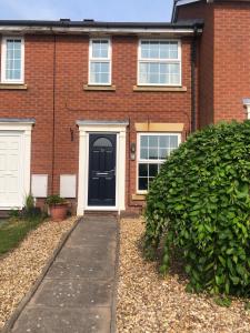 a brick house with a black door and a sidewalk at Homely property close to Princess Royal hospital and Apley Wood in Wellington