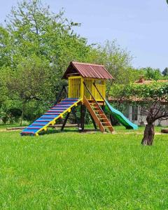 un parque infantil con un tobogán en el césped en Vikendica za odmor, en Banja Luka