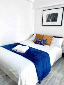 a white bed with a blue blanket on top of it at Studio Apartment in London in London