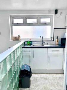 cocina con armarios blancos, fregadero y ventana en Studio Apartment in London en Londres