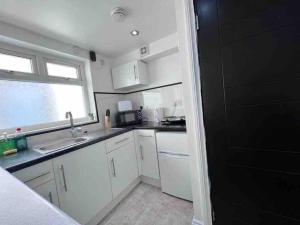 a kitchen with white cabinets and a sink and a window at Studio Apartment in London in London