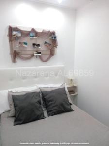 uma cama com duas almofadas num quarto em Nazarena na Nazaré