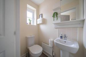 La salle de bains blanche est pourvue de toilettes et d'un lavabo. dans l'établissement 2 bed house near Ricoh Arena, 2xparking, wifi, à Longford