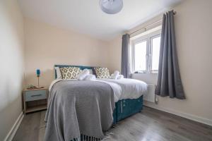 a bedroom with a bed with a blue blanket and a window at 2 bed house near Ricoh Arena, 2xparking, wifi in Longford