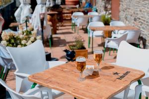 two glasses of beer on a wooden table with white chairs at Pierre & Vacances Aparthotel La Tulipa in Ordino