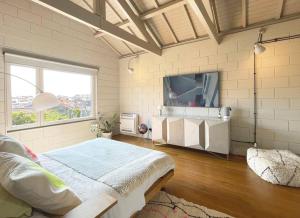 a bedroom with a large bed and a tv at Fabrica No Jardim in Porto