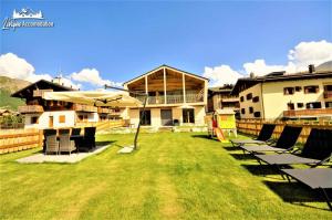 a yard with chairs and umbrellas in front of a building at Radici Relais Sulle Piste da sci vicino a Lupigno in Livigno