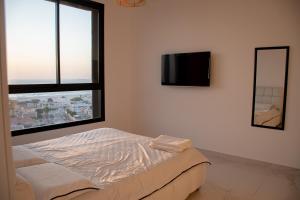 1 dormitorio con 1 cama y TV en la pared en דירת 5 חדרים בבניין הכי טוב בעיר עם נוף מרהיב לים, en Ashdod