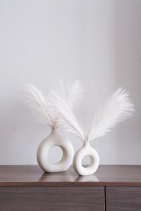 two white vases with white feathers on top of a dresser at BohoChic YasIsland: Beside “F1” in Abu Dhabi