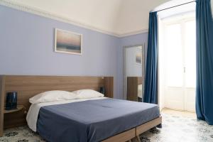 1 dormitorio con cama con sábanas azules y ventana en Le tre rondini, en Barletta