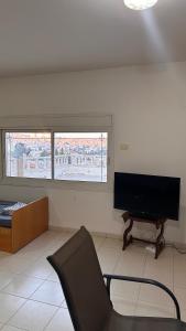 ein Wohnzimmer mit einem Stuhl und einem Flachbild-TV in der Unterkunft ELIAS Penthouse in Nazareth