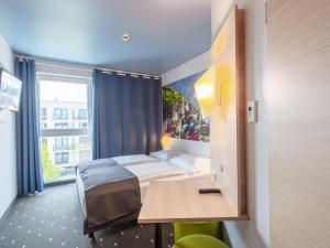 um quarto com uma cama, uma mesa e uma janela em B&B Hotel Neu-Ulm em Neu-Ulm