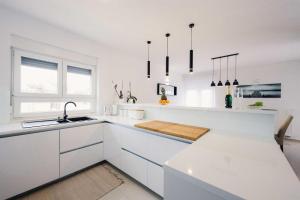 a white kitchen with white cabinets and a sink at Villa Miranda with pool in Zaton