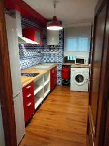 a kitchen with red cabinets and a washing machine at Apartamento Con Encanto San Basilio in Córdoba