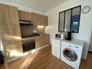 eine Küche mit einer Waschmaschine und einer Mikrowelle in der Unterkunft Appartement du bonheur ! Av de la Mer in Saint-Jean-de-Monts