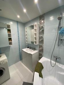 a bathroom with a sink and a washing machine at Suite Apartment in Šiauliai