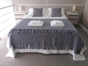 1 dormitorio con 1 cama en blanco y negro y 2 toallas en Loft Premium Torres RS, en Torres