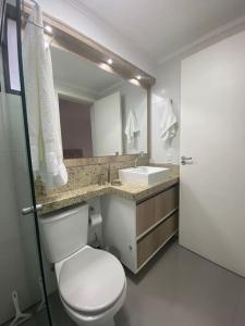 y baño con aseo blanco y lavamanos. en Loft Premium Torres RS, en Torres
