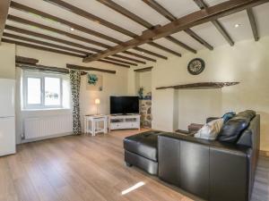 a living room with a leather couch and a television at The Granary in Ripon