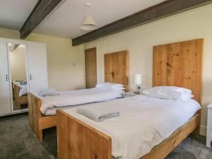 2 camas en un dormitorio con cabeceros de madera en The Hayloft en Ripon