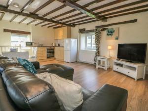 a living room with a leather couch and a television at The Granary in Ripon