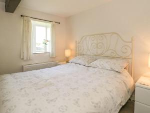 a bedroom with a bed with a white bedspread and a window at The Granary in Ripon