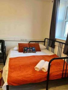 a bed with an orange blanket and pillows on it at Spacious Studio flat in Central London in London