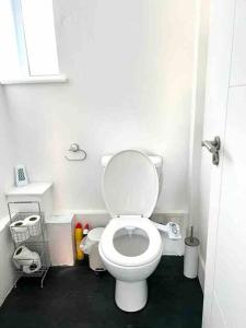 a bathroom with a white toilet and a black floor at Spacious Studio flat in Central London in London