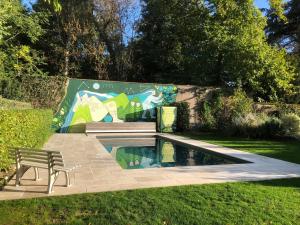 a bench sitting next to a pool with a mural at Les Haltes du Clos du Petit Dannezy in Cour-Cheverny