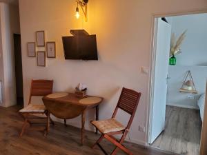 Habitación con mesa, 2 sillas y TV. en "Le Rive-Gauche" appartement tout équipé, 2 chambres à 2 pas de la gare -- WiFi - TV connectée en Châlons-en-Champagne