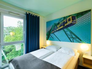 ヴッパータールにあるB&B HOTEL Wuppertal City-Südの壁に列車の絵画が描かれたベッドルーム