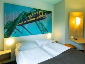 ヴッパータールにあるB&B HOTEL Wuppertal City-Südのベッドルーム(電車の絵画付)